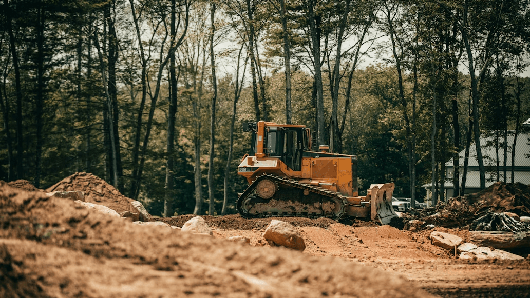Bulldozer clearing land on development site with brown clay soil